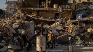 Sursă foto:cnn,com; Oameni stau lângă o casă distrusă după cutremurul din Antakya, în sud-estul Turciei